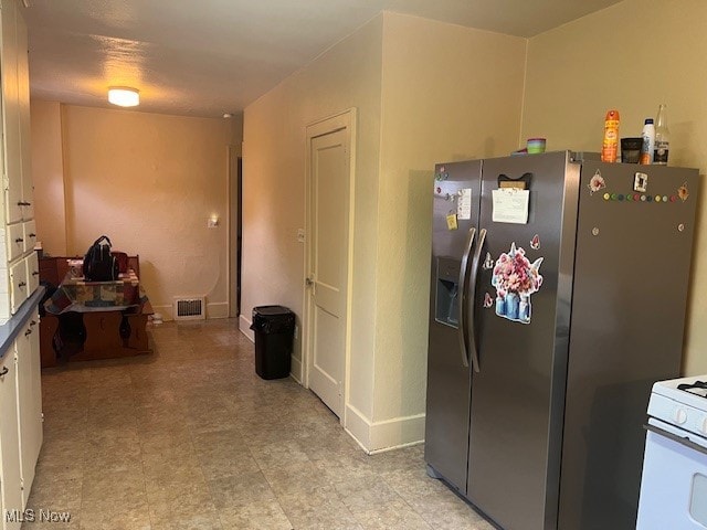 kitchen with white cabinets, stainless steel fridge with ice dispenser, and white gas range oven