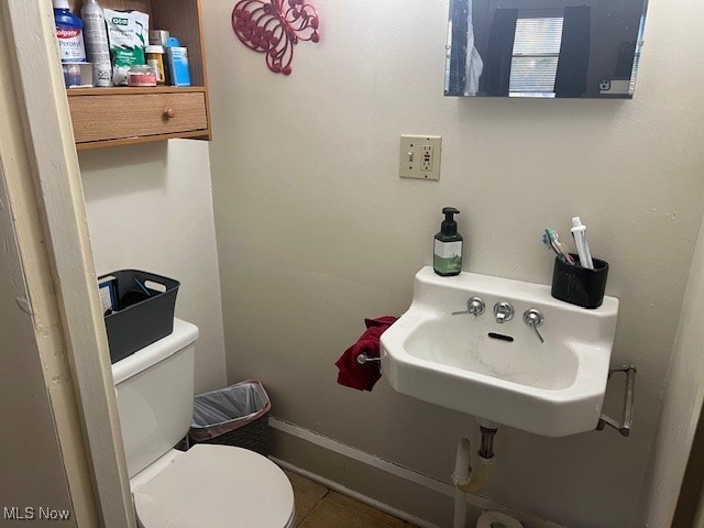 bathroom with toilet, tile patterned floors, and sink