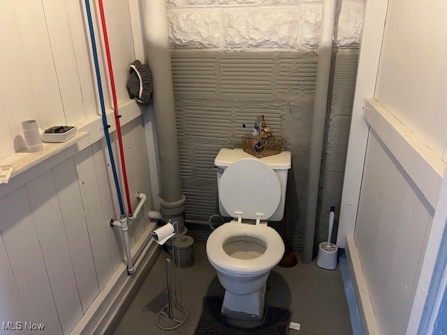 bathroom with wood walls and toilet