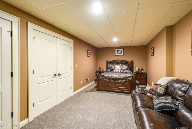 carpeted bedroom featuring a drop ceiling and a closet