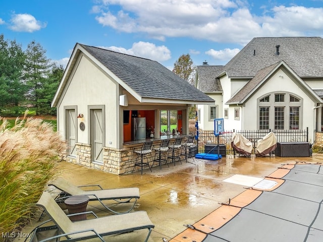 rear view of house with an outdoor bar and a patio