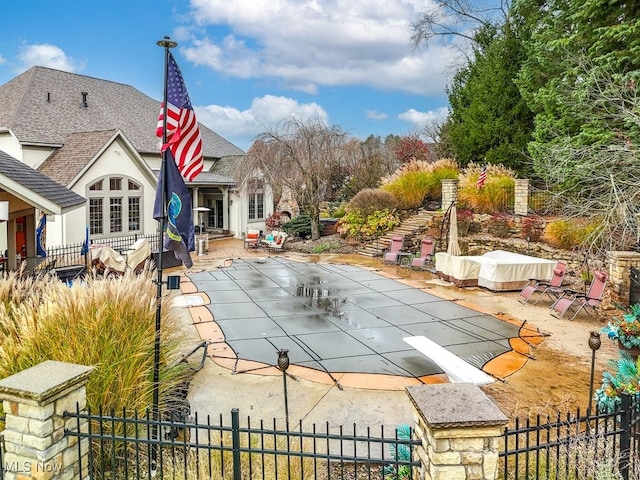 view of swimming pool with a diving board and a patio