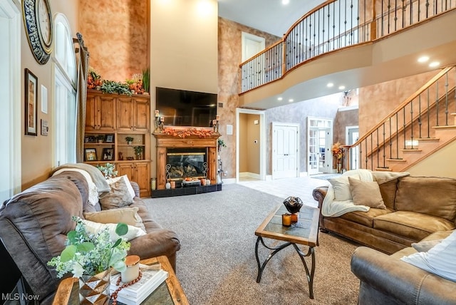 living room with a towering ceiling and light colored carpet