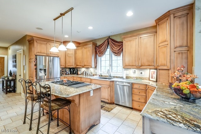 kitchen featuring light stone counters, stainless steel appliances, a center island, hanging light fixtures, and a breakfast bar area