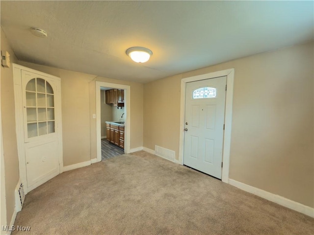 carpeted foyer entrance featuring a sink, visible vents, and baseboards