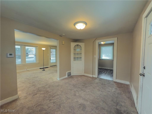 unfurnished room featuring light carpet, plenty of natural light, and visible vents