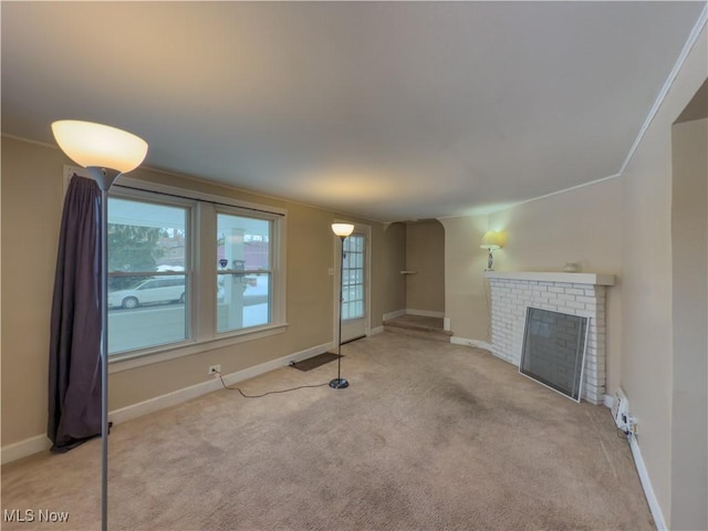 unfurnished living room with light carpet, a fireplace, a baseboard radiator, and ornamental molding