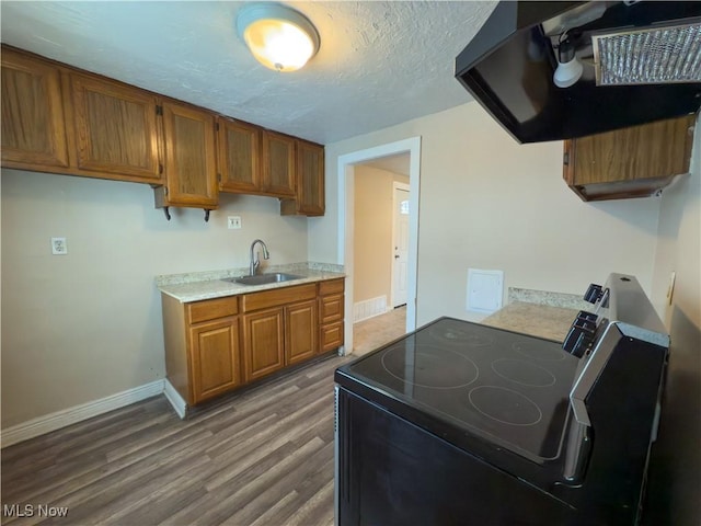 kitchen featuring range hood, light countertops, electric range, brown cabinetry, and a sink