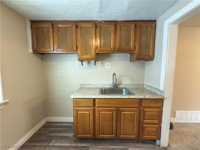 kitchen with brown cabinets, visible vents, light countertops, and a sink