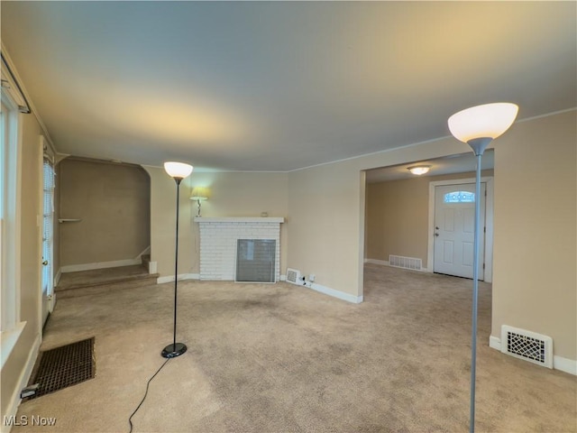 unfurnished living room with light colored carpet and a brick fireplace