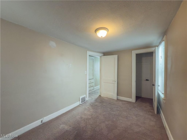 unfurnished bedroom with light carpet, a closet, and a textured ceiling