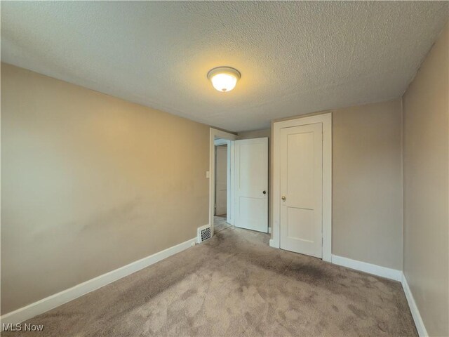 unfurnished bedroom featuring light colored carpet, a textured ceiling, and a closet