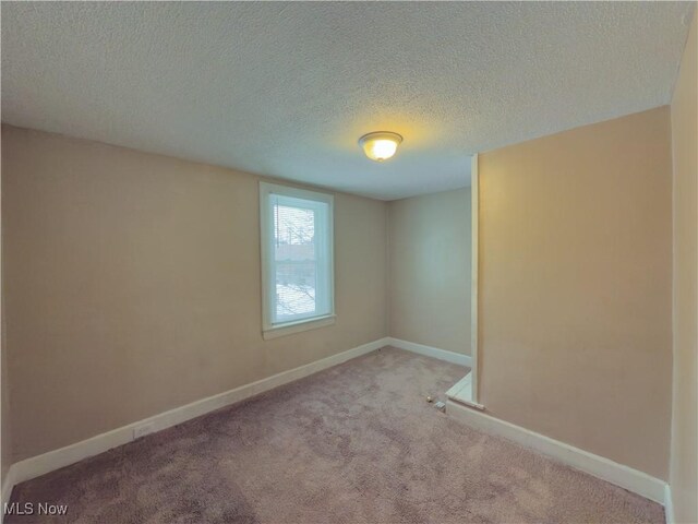 empty room with light colored carpet and a textured ceiling