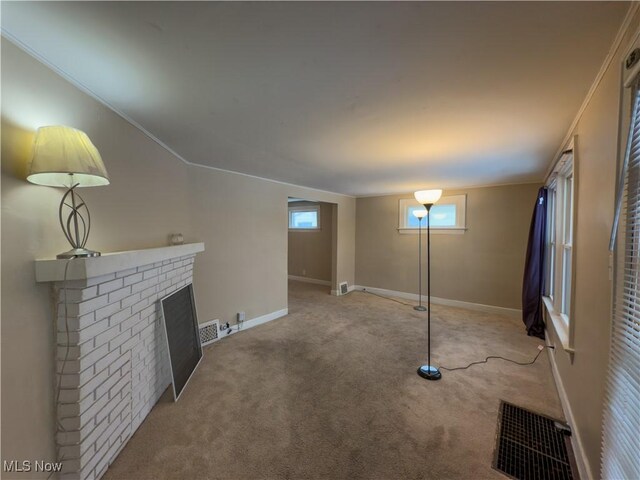 basement with light carpet, a brick fireplace, and crown molding