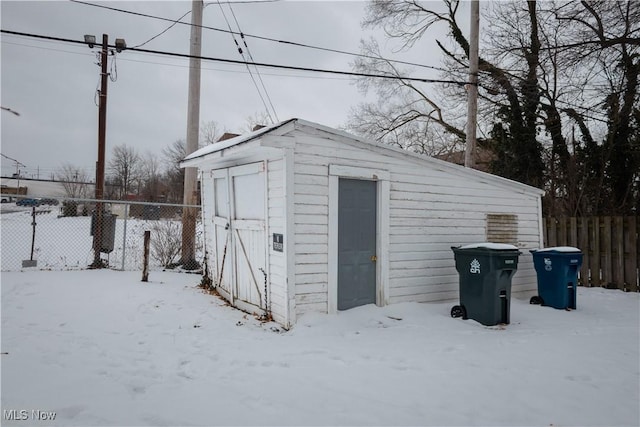 snow covered structure with an outbuilding and fence