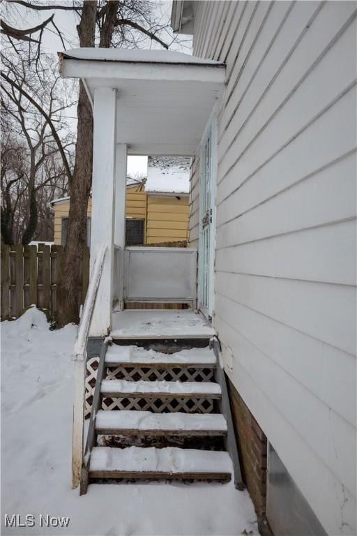 snow covered property entrance with fence