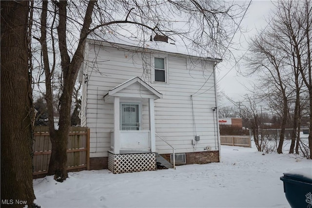 snow covered property with entry steps, fence, and a chimney