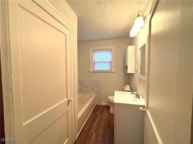 bathroom featuring vanity, hardwood / wood-style flooring, a tub, and toilet