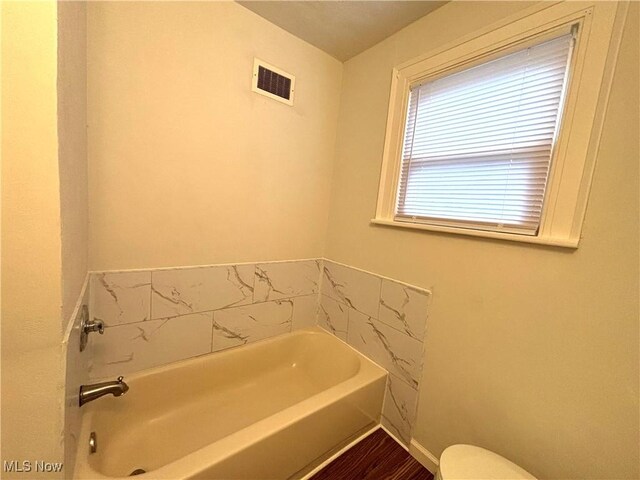 bathroom featuring a bathing tub, wood-type flooring, and toilet