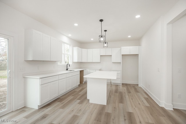 kitchen featuring a center island, a healthy amount of sunlight, white cabinets, and sink