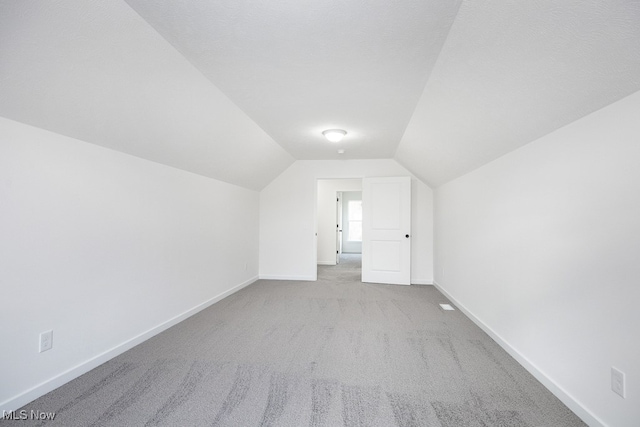 bonus room with light colored carpet and lofted ceiling