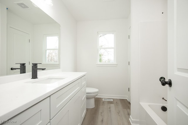 bathroom featuring a wealth of natural light, vanity, wood-type flooring, and toilet