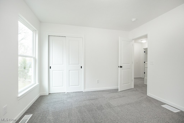 unfurnished bedroom featuring light carpet and a closet