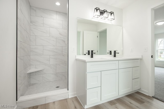 bathroom featuring tiled shower, hardwood / wood-style floors, and vanity