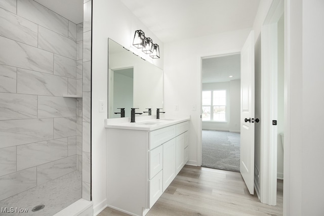 bathroom with a tile shower, hardwood / wood-style floors, and vanity