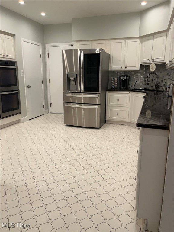 kitchen featuring decorative backsplash, white cabinetry, sink, and appliances with stainless steel finishes