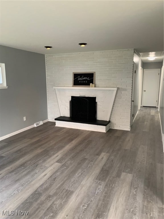 unfurnished living room with dark hardwood / wood-style floors and a brick fireplace