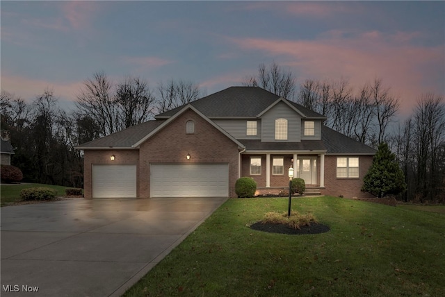 traditional-style home featuring an attached garage, brick siding, driveway, and a yard