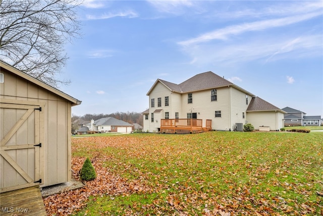 rear view of property with central air condition unit, a yard, a deck, and a storage shed