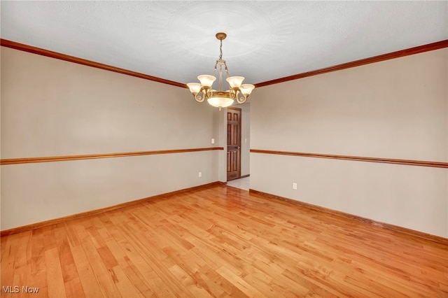 spare room with a notable chandelier, light wood-type flooring, and crown molding