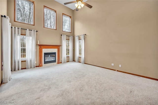 unfurnished living room with a towering ceiling, carpet floors, and a tiled fireplace