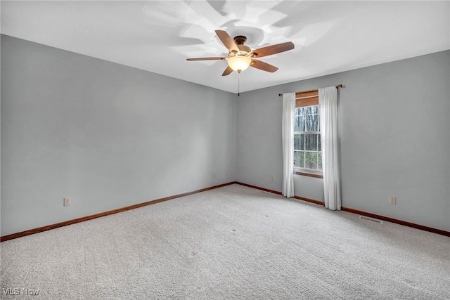 empty room featuring carpet, visible vents, a ceiling fan, and baseboards