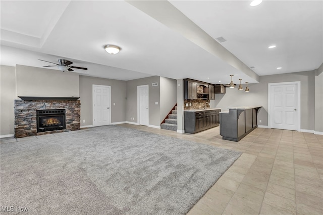 unfurnished living room with ceiling fan, light colored carpet, and a fireplace