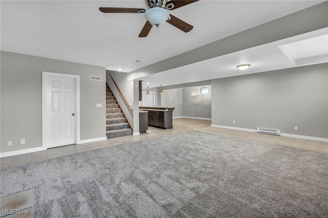 basement featuring visible vents, a ceiling fan, light tile patterned floors, a baseboard radiator, and stairs