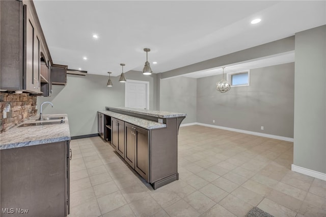 kitchen with dark brown cabinetry, light stone countertops, and decorative light fixtures