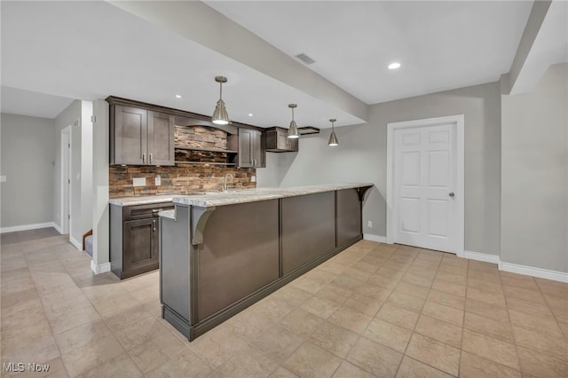 kitchen featuring dark brown cabinetry, visible vents, baseboards, and decorative backsplash
