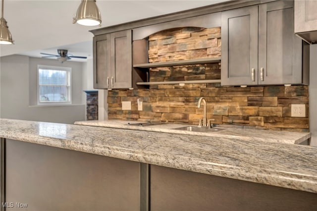 kitchen featuring light stone countertops, decorative backsplash, decorative light fixtures, and sink