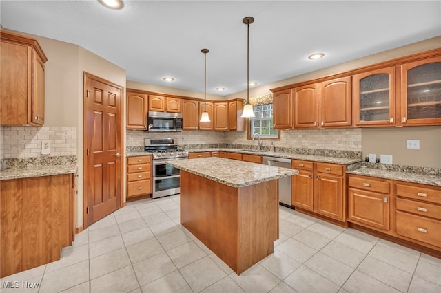 kitchen with a sink, light stone countertops, a kitchen island, and stainless steel appliances