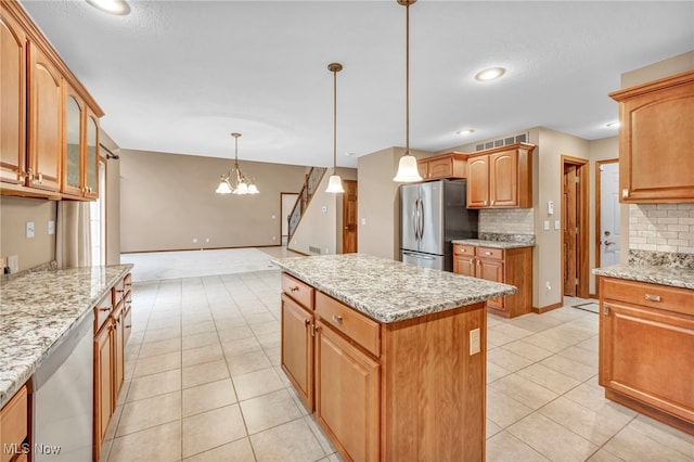 kitchen with light stone countertops, stainless steel appliances, pendant lighting, a notable chandelier, and a kitchen island