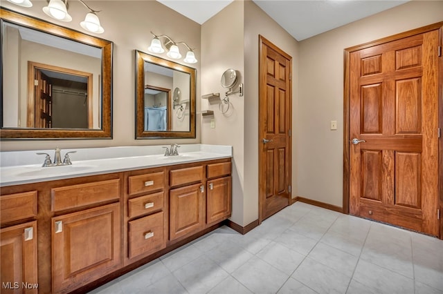 bathroom with double vanity, tile patterned floors, baseboards, and a sink