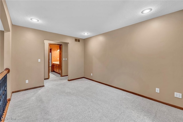 unfurnished room featuring light carpet and a textured ceiling