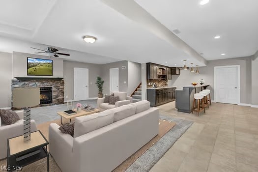 living area with baseboards, stairway, a stone fireplace, recessed lighting, and a ceiling fan