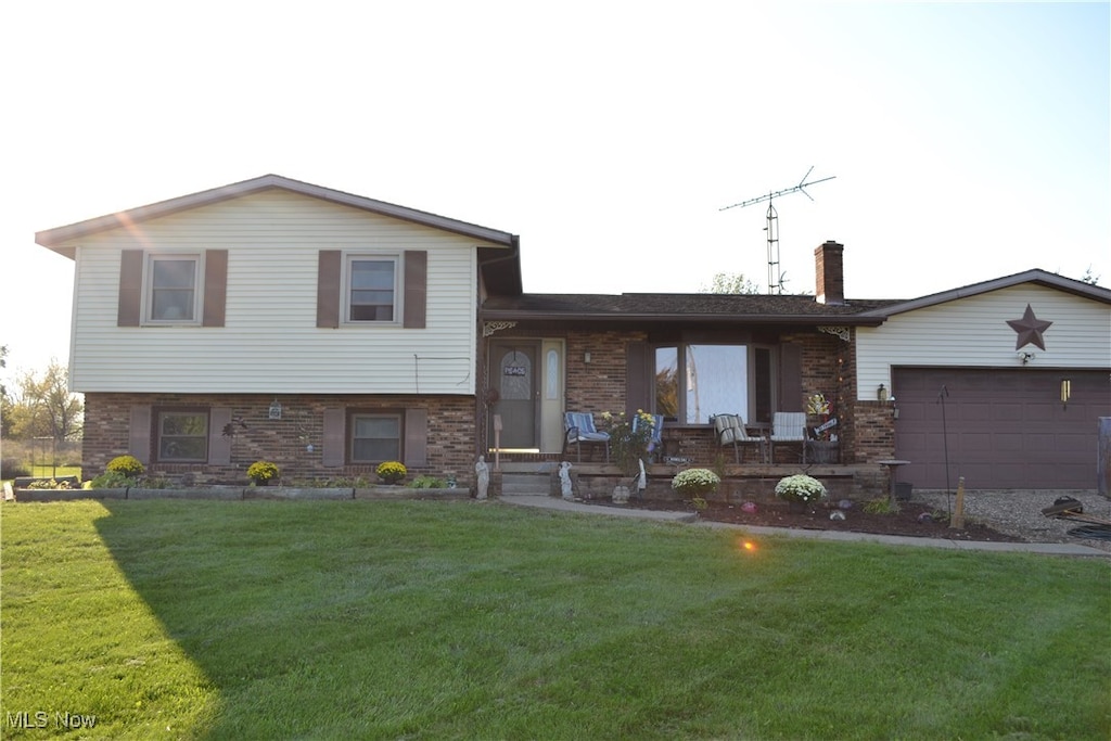 tri-level home featuring a garage and a front lawn