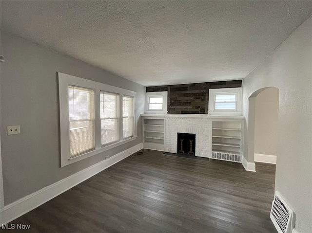 unfurnished living room featuring a fireplace, dark hardwood / wood-style flooring, and a textured ceiling