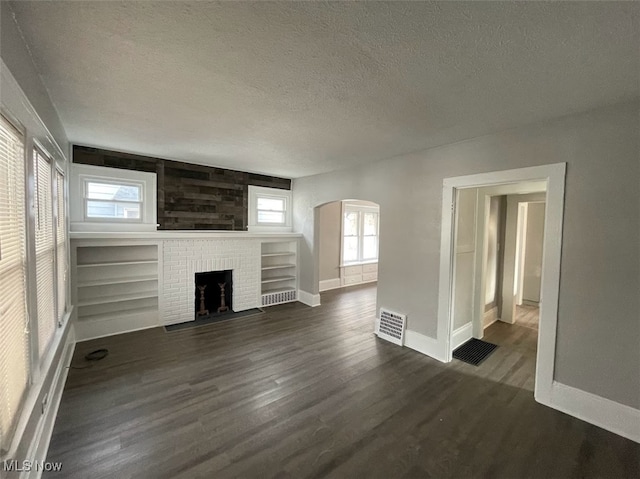 unfurnished living room featuring dark hardwood / wood-style flooring, a healthy amount of sunlight, and a textured ceiling