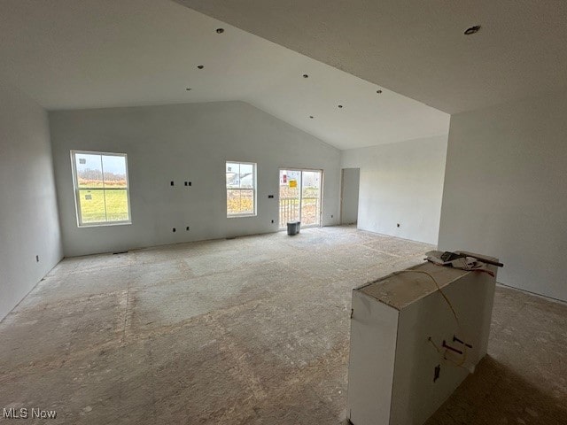 unfurnished living room with a wealth of natural light, light colored carpet, and vaulted ceiling